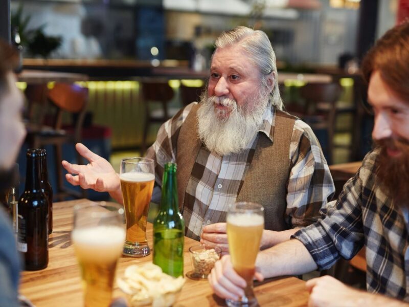 Menschen diskutieren bei Bier an einem Tisch in einer Kneipe