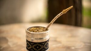Traditioneller Mate-Becher mit Kräuteraufguss und Bombilla auf einem Holztisch