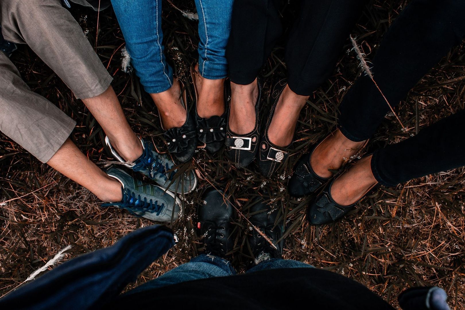 Mehrere Menschen stehen im Kreis und berühren sich mit ihren Schuhen